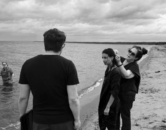 A film crew gathers beside the water.